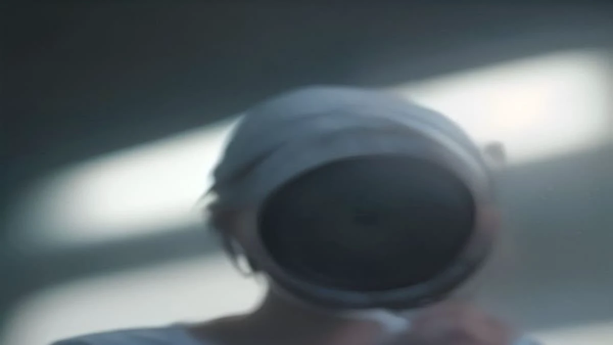 slight low angle of a quality inspector in a clean facility holding a magnifier over a manufactured part, soft morning light (illustrative image)